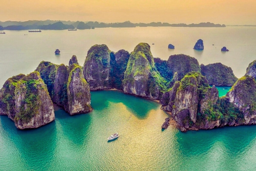 Halong Bay limestone islands with cruise boat in emerald water – Auasia Travel